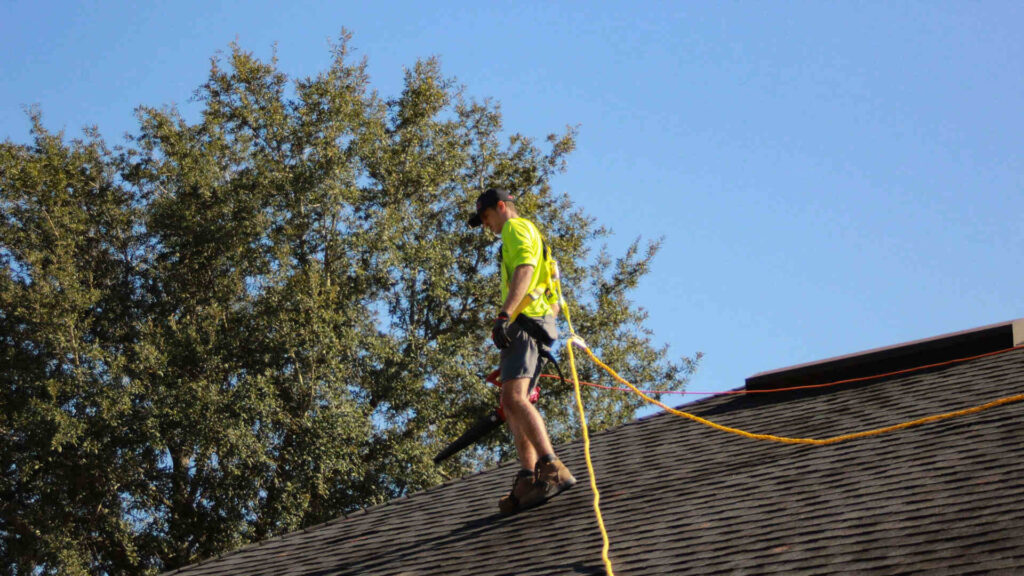 Roofer wearing safety harness conducting roof inspection